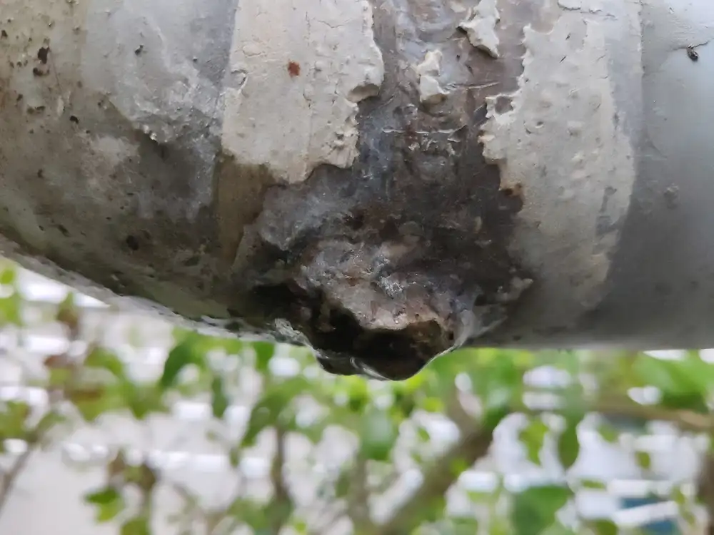 Gota de agua que se forma bajo una zona oxidada y desconchada de una tubería metálica